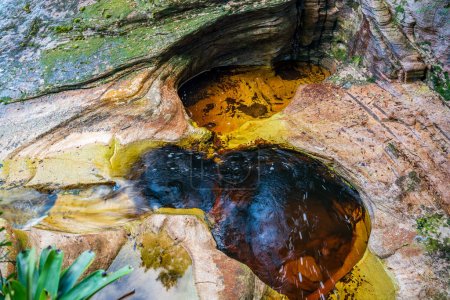 Ruhiges Becken inmitten farbenfroher, strukturierter Felsen.