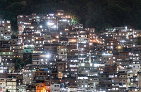 Téléchargez les photos : Une colline de favela densément construite qui brille sous les lumières de la nuit - en image libre de droit