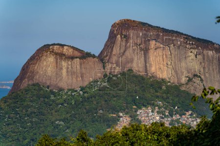 Abenteurer Gipfel Rios Two Brothers Rock mit Rocinha Favela am Fuße, die einen krassen Kontrast zur urbanen Natur aufweist.