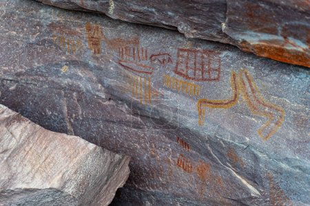 Colorful ancient petroglyphs with symbolic imagery etched on stone captured in a detailed photograph.