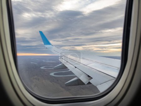 Puesta de sol y vista del ala del avión desde la ventana de vuelo.