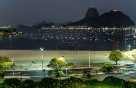 Friedlicher Abend mit Booten und beleuchtetem Fußweg durch die Bucht von Rio de Janeiros.