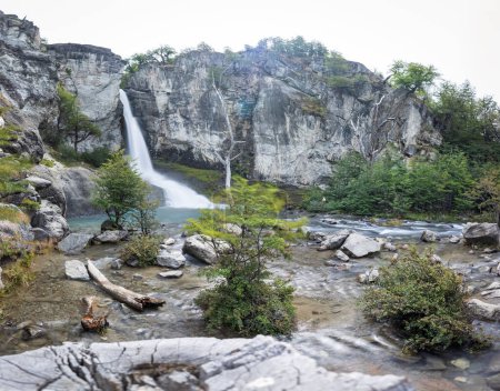 Heiterer Wasserfall mündet in einen ruhigen Pool, flankiert von steilen Klippen und üppigem Grün.