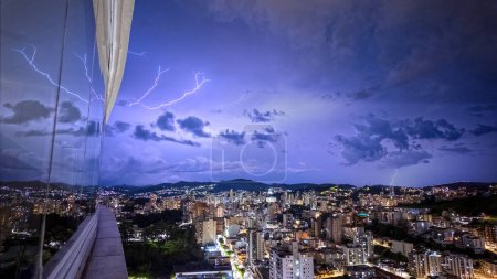 Lightning storm lights up night sky over city.