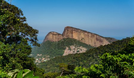 Twin rock formations tower over Rios largest favela, Rocinha, amid lush greenery.