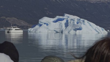 Tourists on a boat trip view an iceberg in arctic waters.