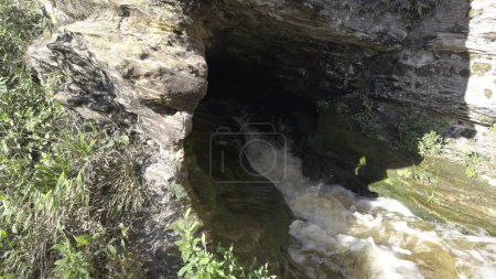 Slow-mo vidéo montre une rivière qui coule d'une grotte au milieu d'une forêt luxuriante.
