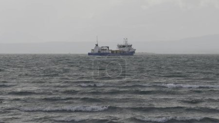 Fishing boat endures rough seas and cloudy weather, conveying a grim day at sea.