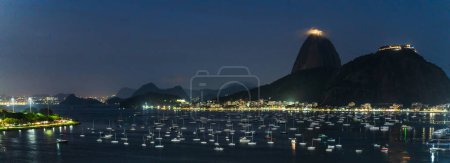 Un panorama nocturno de Río con barcos e iluminación de la ciudad bajo las estrellas.