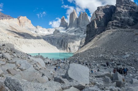 Los viajeros caminan por senderos accidentados hacia un impresionante lago helado en medio de picos imponentes.