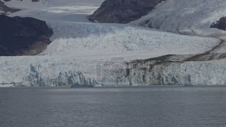 Tourists on a boat observe the immense Spegazzini Glacier in Argentina, appreciating the grandeur of nature.