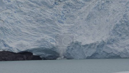 Riesige Eisstücke fallen vom Gletscher und bilden Spritzer und Eisberge.