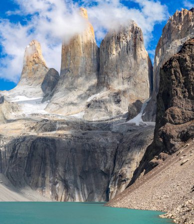Picos de granito se elevan por encima de un lago glacial bajo cielos azules claros. torres del paine