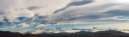Majestic lenticular clouds at sunset over serene mountains.