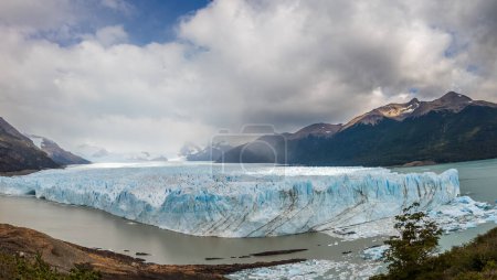 Gran glaciar en medio de montañas bajo un llamativo cielo nublado.