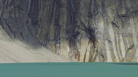 Schmelzender Gletscher speist Bäche, die an Klippen in einen türkisfarbenen See münden.