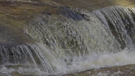 Vídeo en cámara lenta mostrando agua clara fluyendo sobre rocas.