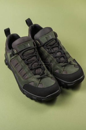 Téléchargez les photos : Baskets militaires sur fond vert. Chaussures armée kaki - en image libre de droit