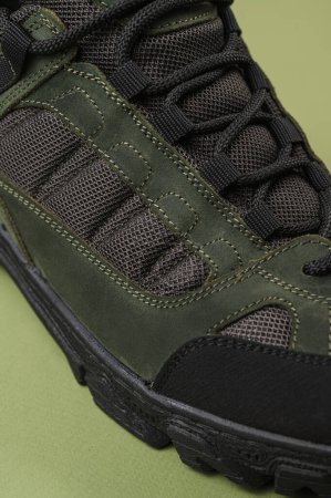 Téléchargez les photos : Baskets militaires sur fond vert. Chaussures armée kaki - en image libre de droit