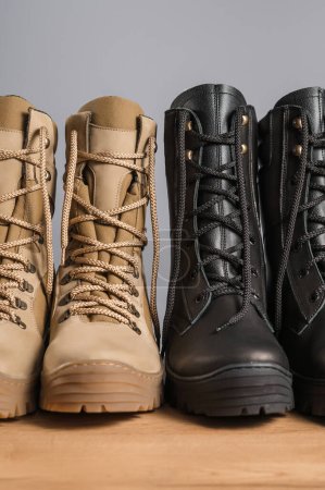Photo for Khaki and black tall military boots on a gray background - Royalty Free Image