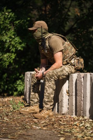 Téléchargez les photos : Un soldat militaire en uniforme spécial avec un sac à dos tactique près d'un bâtiment détruit - en image libre de droit