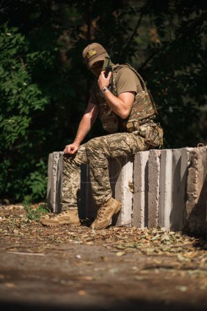 Téléchargez les photos : Un soldat militaire en uniforme spécial avec un sac à dos tactique près d'un bâtiment détruit - en image libre de droit