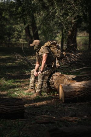 Téléchargez les photos : Un soldat militaire en uniforme spécial avec un sac à dos tactique dans la forêt - en image libre de droit