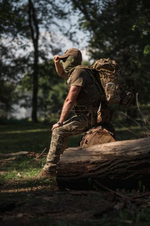 Téléchargez les photos : Un soldat militaire en uniforme spécial avec un sac à dos tactique dans la forêt - en image libre de droit