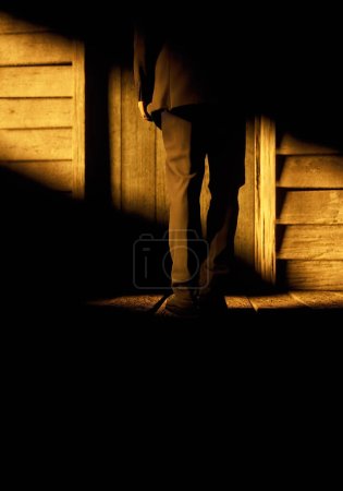 Man stands in sunlight in front of front door of old wooden house. 3D render.
