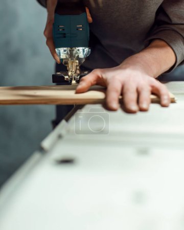 Téléchargez les photos : Homme scies étagère en bois sur table de scie avec scie sauteuse. - en image libre de droit