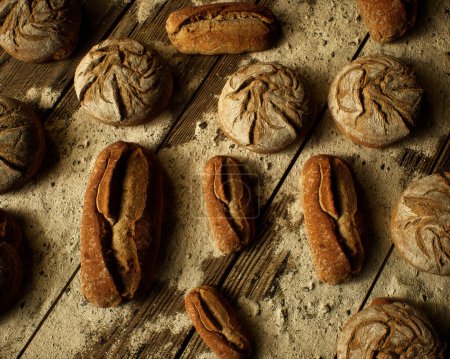 Foto de Rollos de pan sobre mesa de madera con harina. Vista superior. - Imagen libre de derechos
