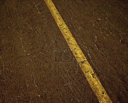 Foto de Desgastado y agrietado asfalto viejo de una carretera con una línea divisoria amarilla. Detalle de disparo. - Imagen libre de derechos