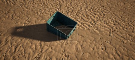 Foto de Caja de plástico azul que yace en la arena ondulada de la playa. - Imagen libre de derechos