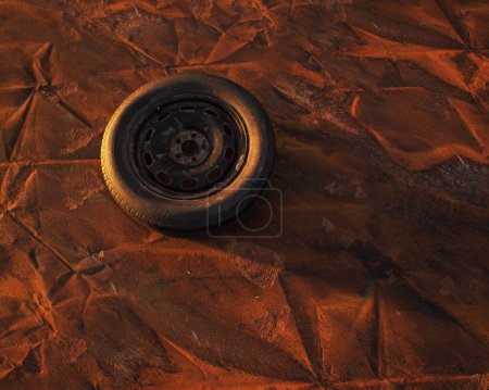 Old car wheel on weathered rusty painted metal sheet.