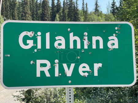 Ein aufgeschossenes Schild Gilahina River, The McCarthy Road, Alaska. Hochwertiges Foto