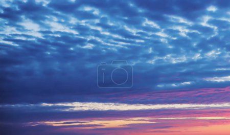 Photo for Scenic bright background. Natural sunset background, dark blue clouds and light pink clouds backlit by the setting sun - Royalty Free Image