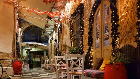 Téléchargez les photos : Noël saison rue café à ioannina ville grèce lumières tables chaises rue piétonne comme échiquier - en image libre de droit