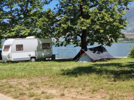 Photo for Caravan car  and trailer  tent by the lake and green platanus trees in summer holidays adventure - Royalty Free Image