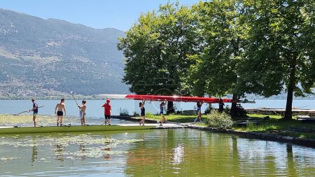 Foto de Remo remeros trainnnng en el lago pamvotis bajo los árboles de ioannina en la temporada de verano griego - Imagen libre de derechos