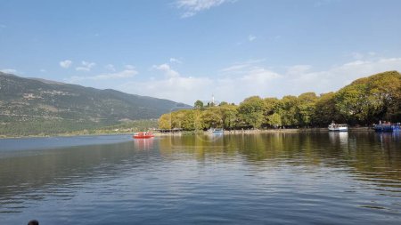 Téléchargez les photos : Ioannina ou giannena en automne sesaon lac arbres bateaux couleurs bleu ciel reflets grec - en image libre de droit