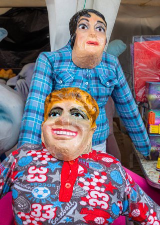 Foto de Cuenca, Ecuador - 29 de diciembre de 2022: Muñecas de trapo o muñecos con máscaras divertidas, cómicas o políticas se ofrecen a la venta en un mercado callejero para que los monigotes se quemen para celebrar la víspera de Año Nuevo - Imagen libre de derechos