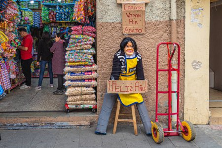 Foto de Cuenca, Ecuador - 31 de diciembre de 2022: Tradición popular de Ecuador. Un monigote se encuentra en la entrada de la tienda que puede traer suerte en el próximo año. Inscripción 'Maldita sea, baje' y 'Feliz Año Nuevo' - Imagen libre de derechos