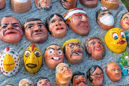 Foto de Cuenca, Ecuador - 29 de diciembre de 2022: Máscaras divertidas, cómicas y políticas para Monigotes o muñecas de trapo en un mercado callejero. Los monigotes serán quemados a medianoche para celebrar el Año Nuevo. Tradición de Ecuador - Imagen libre de derechos