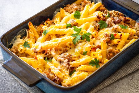 Pasta penne with minced meat, cheese and creamy sauce. Mac and cheese. Baked dish, close up.