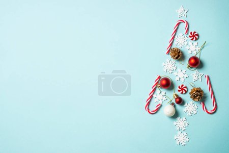 Christmas fir tree with holiday decorations on blue background. Top view with copy space.