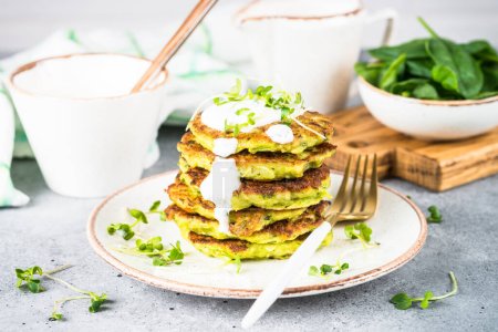 Zucchini pancakes with spinach, hepbs and parmesan cheese, served with sour cream or yogurt. Diet food, meatless dish.