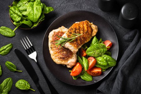Photo for Grilled Meat. Pork steaks with fresh salad. Top view image at black table. keto diet lunch. - Royalty Free Image