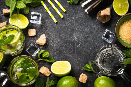 Téléchargez les photos : Cocktail mojito avec des ingrédients sur fond de pierre noire. Boisson estivale mojito au citron vert, rhum, menthe et glace. Vue supérieure avec espace de copie. - en image libre de droit