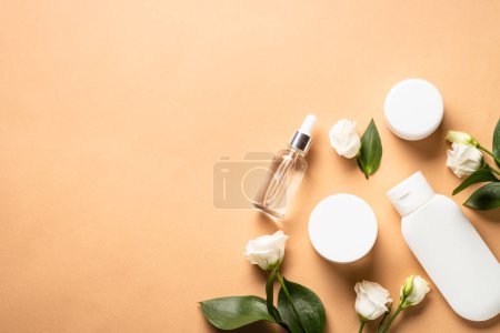 Téléchargez les photos : Natural cosmetic products at color background. Cream, serum, tonic with green leaves and flowers. Flat lay image with copy space. - en image libre de droit