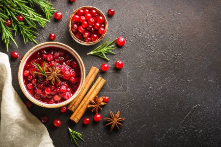 Photo for Cranberry sauce in a bowl with rosemary and spices. Top view at black background. - Royalty Free Image